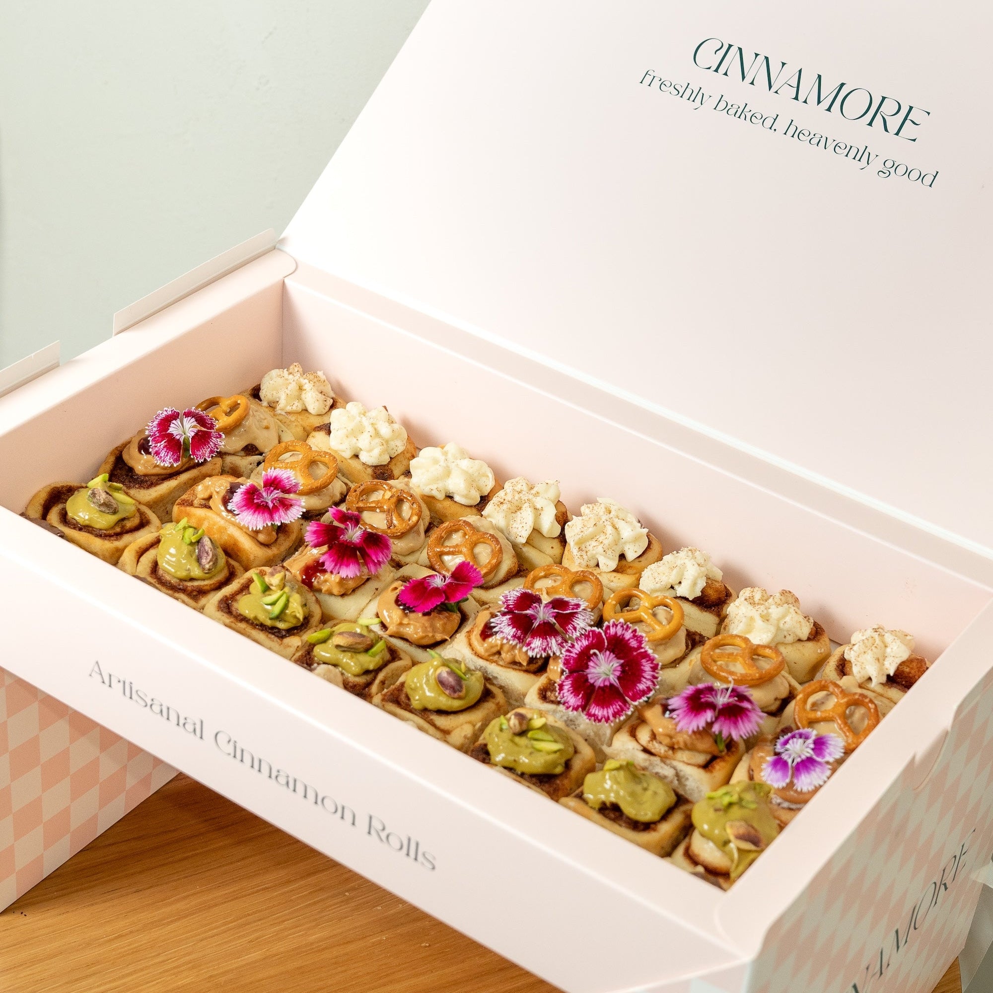 Box of mini cinnamon rolls with decorative flowers on a light background