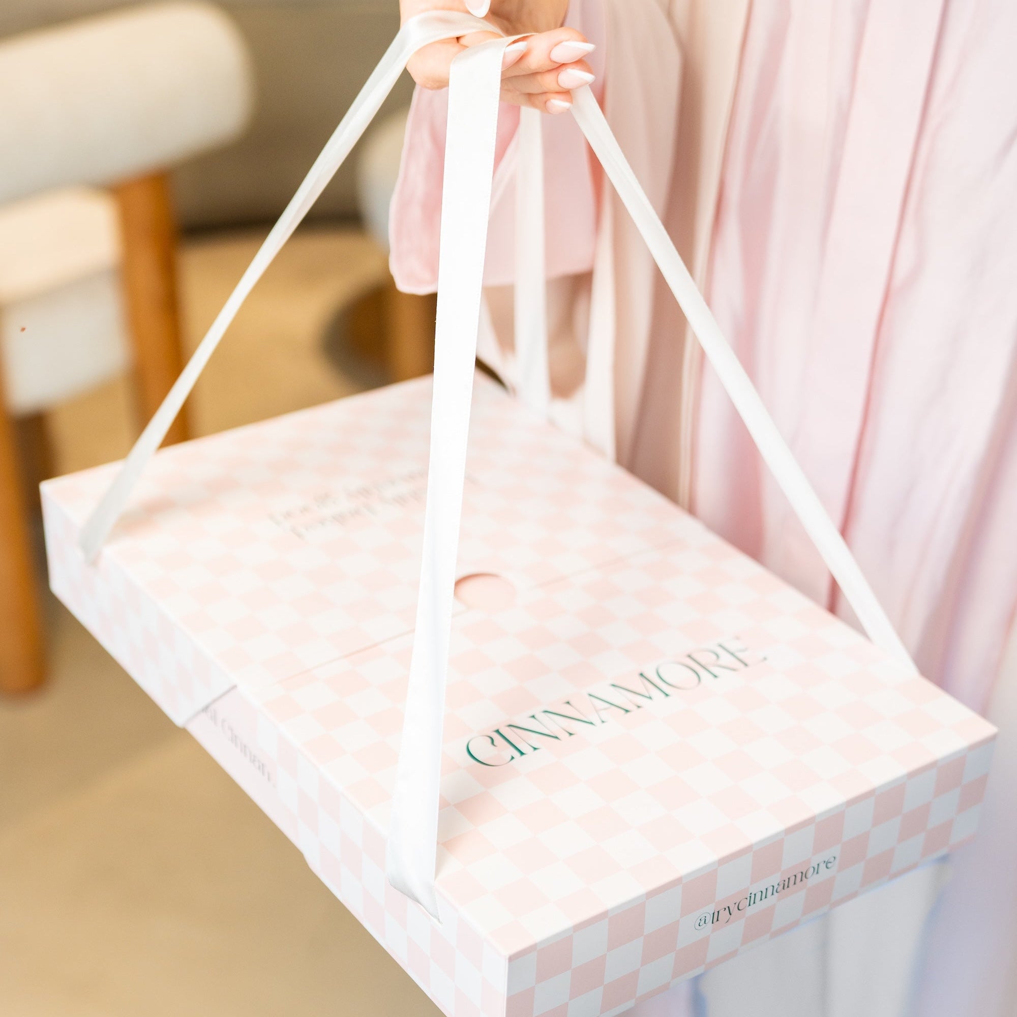 Person holding a giftibg box with "CINNAMORE" mini cinnamon rolls