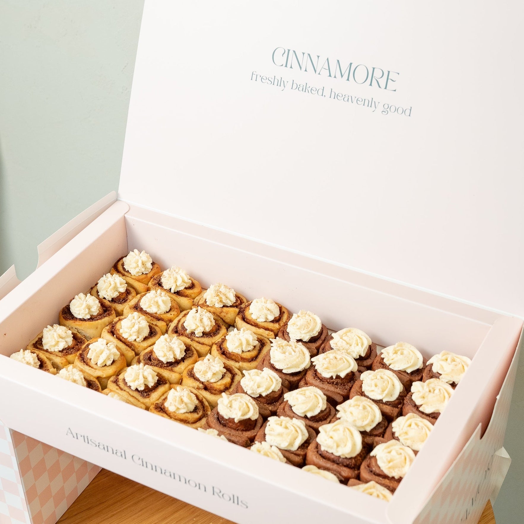 Box of mini protein cinnamon rolls with 'CINNAMORE' branding on a light background